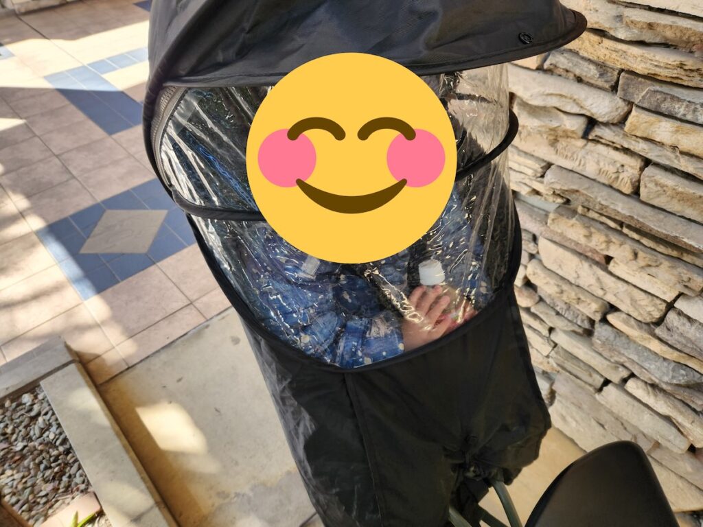 ギュットクルームR・DXのリアチャイルドシートにレインカバーを装着して子どもが乗っている様子